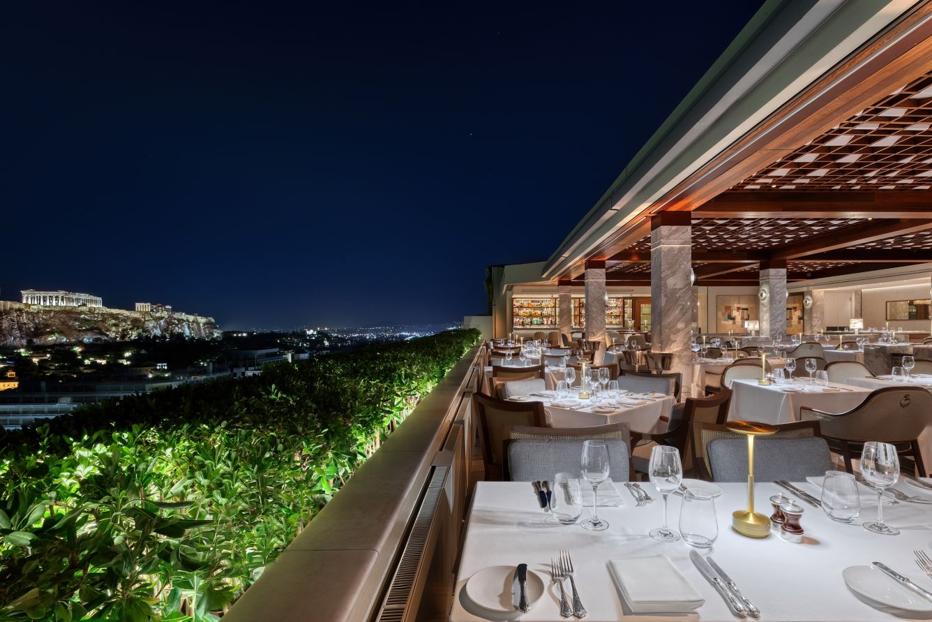 Athens rooftop bar at dusk with the Acropolis lit on the skyline