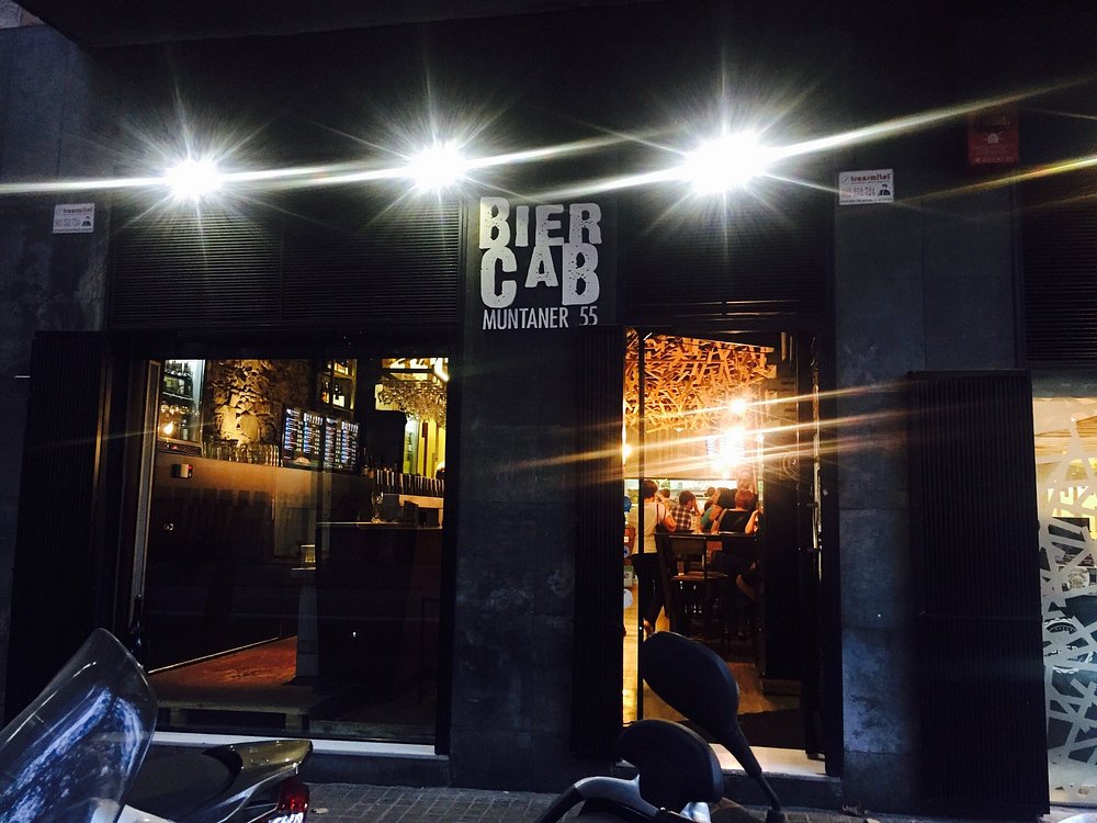 A craft beer bar with a long row of taps and screens listing the pours at BierCaB, Barcelona