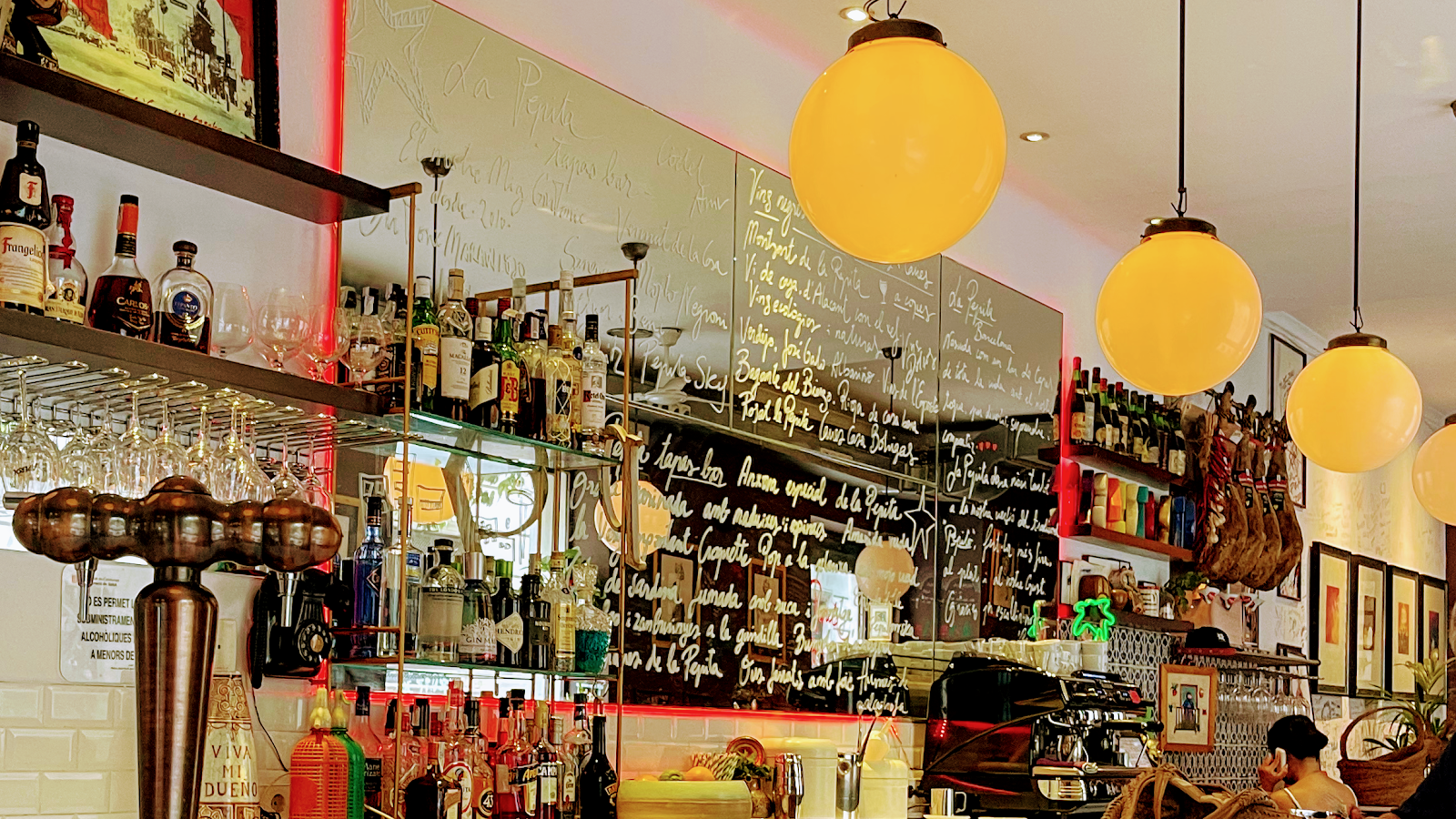 Small tapas bar counter with vermouth bottles and plates in Gracia Barcelona