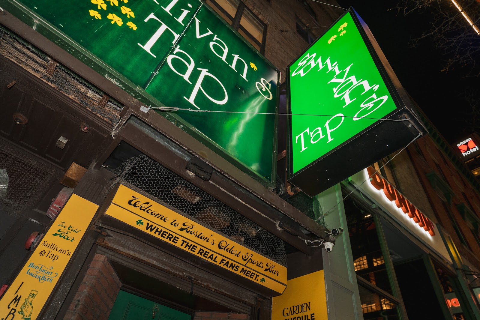 Long wooden bar with taps and televisions, in the style of Sullivan's Tap on Canal Street in Boston