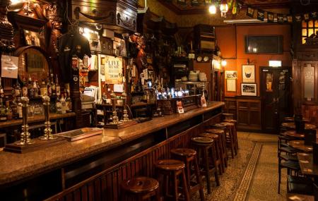 Dark Victorian pub interior with carved bar and a small performance corner at The International Bar Dublin