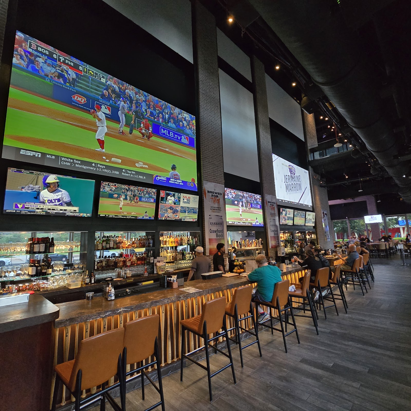 Two-story sports bar interior with rows of screens in downtown Houston