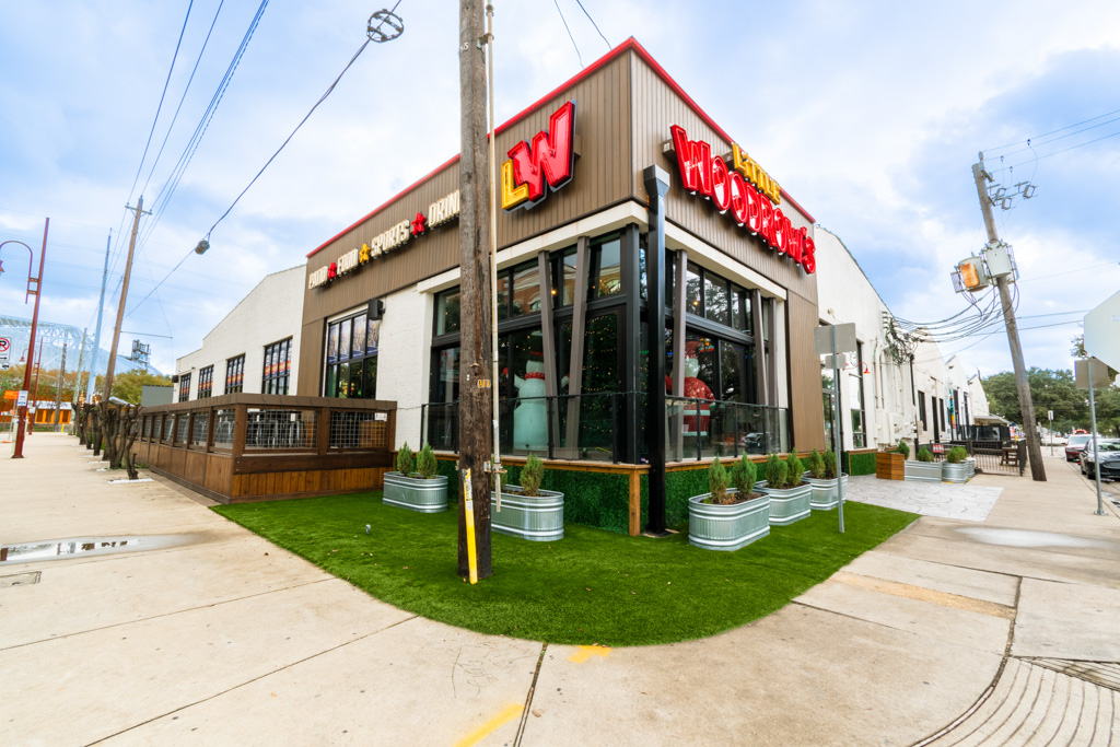 Open patio sports bar with picnic tables and screens in EaDo Houston