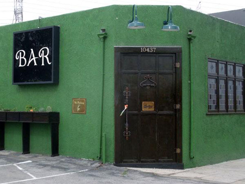 A dim, antique-filled bar room with a small stage, in the style of The Other Door, North Hollywood
