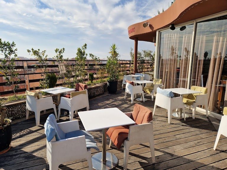 Sky Bar rooftop pool terrace at Es Saadi Palace, Marrakech, with Atlas Mountain panorama at sunset